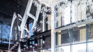 A modern interior with a high ceiling, hanging spherical light fixtures, and a seating area with a sofa and armchairs. - Hampton by Hilton Stockton on Tees (Stockton-on-Tees)