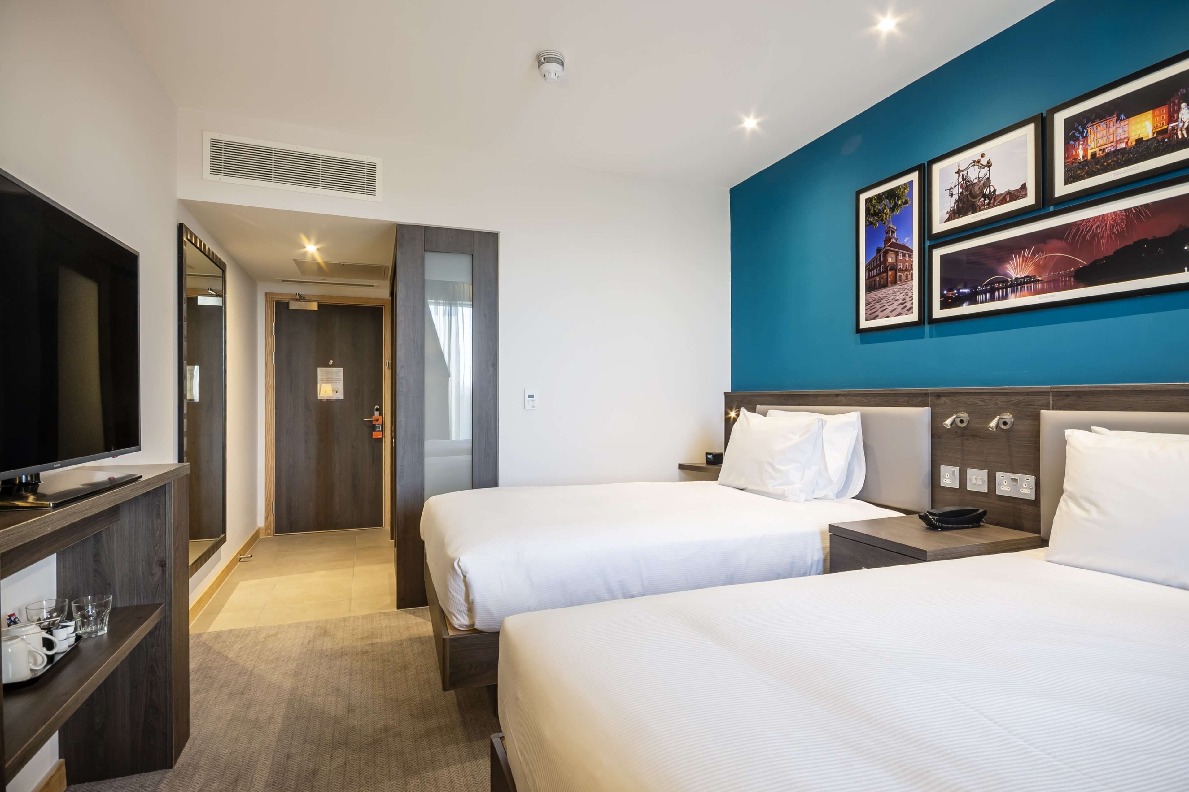 A hotel room with two beds, a TV, a desk, and a nightstand.
