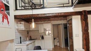 A modern kitchen with white cabinets, a dining table, and a hanging light fixture. - House 75m2 air-conditioned + garage, all comforts, located medieval center Cahors. (Cahors)
