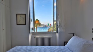 Un dormitorio con cama, ventana y vistas al mar, además de un radiador.