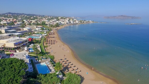 Un complejo turístico costero con piscina, playa y mar azul cristalino.
