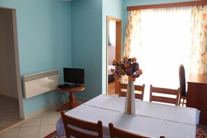 Enjoy meals at the dining table with a vase of flowers and a TV for entertainment.