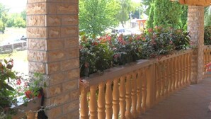 A covered outdoor area with stone pillars, a wooden ceiling, and a railing with flowers. - Apartments and rooms Ivanka, (13914), Rakovica, hr (Rakovica)