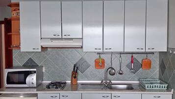 Een koelkast, een magnetron, kookgerei, borden en bestek