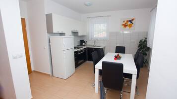 Een koelkast, een magnetron, een vaatwasser, kookgerei, borden en bestek