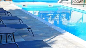 Une piscine avec des chaises longues et un espace abrité.