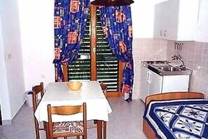 Cozy retreat with a compact kitchenette, single bed, and dining area.