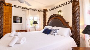 Une chambre d’hôtel avec un grand lit, une tête de lit en bois, un téléviseur à écran plat et une fenêtre avec des rideaux.