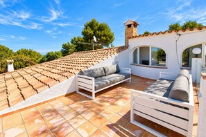 Eine Dachterrasse mit einer weißen Couch, einem kleinen Bett und einem Essbereich.
