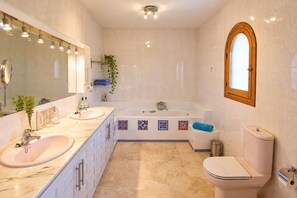 Un baño moderno con lavamanos doble, bañera y retrete.