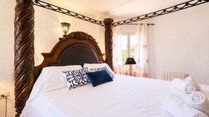 A hotel room with a large bed, a wooden headboard, a bedside lamp, and a window with curtains.