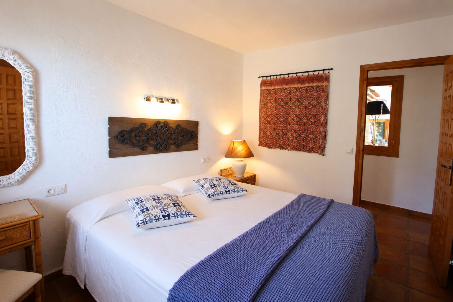 A bedroom with a bed, bedside lamp, wall decor, and a door.