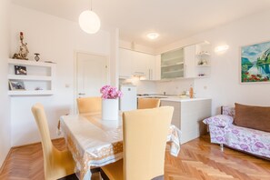 Cozy living space with a dining area for two, a compact kitchen, and a comfortable sofa.