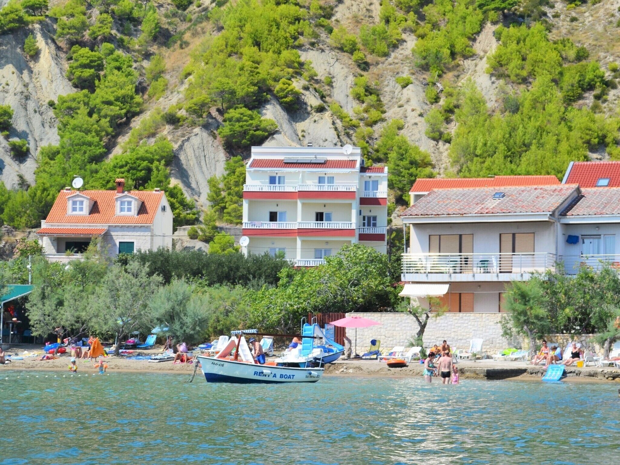Zona costera con edificios, una playa y embarcaciones.