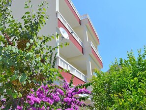 Stunning building with lush greenery and vibrant flowers surrounds this multi-story residence.