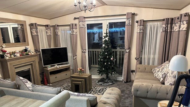 Een woonkamer met een open haard, een televisie, een kerstboom en twee banken.