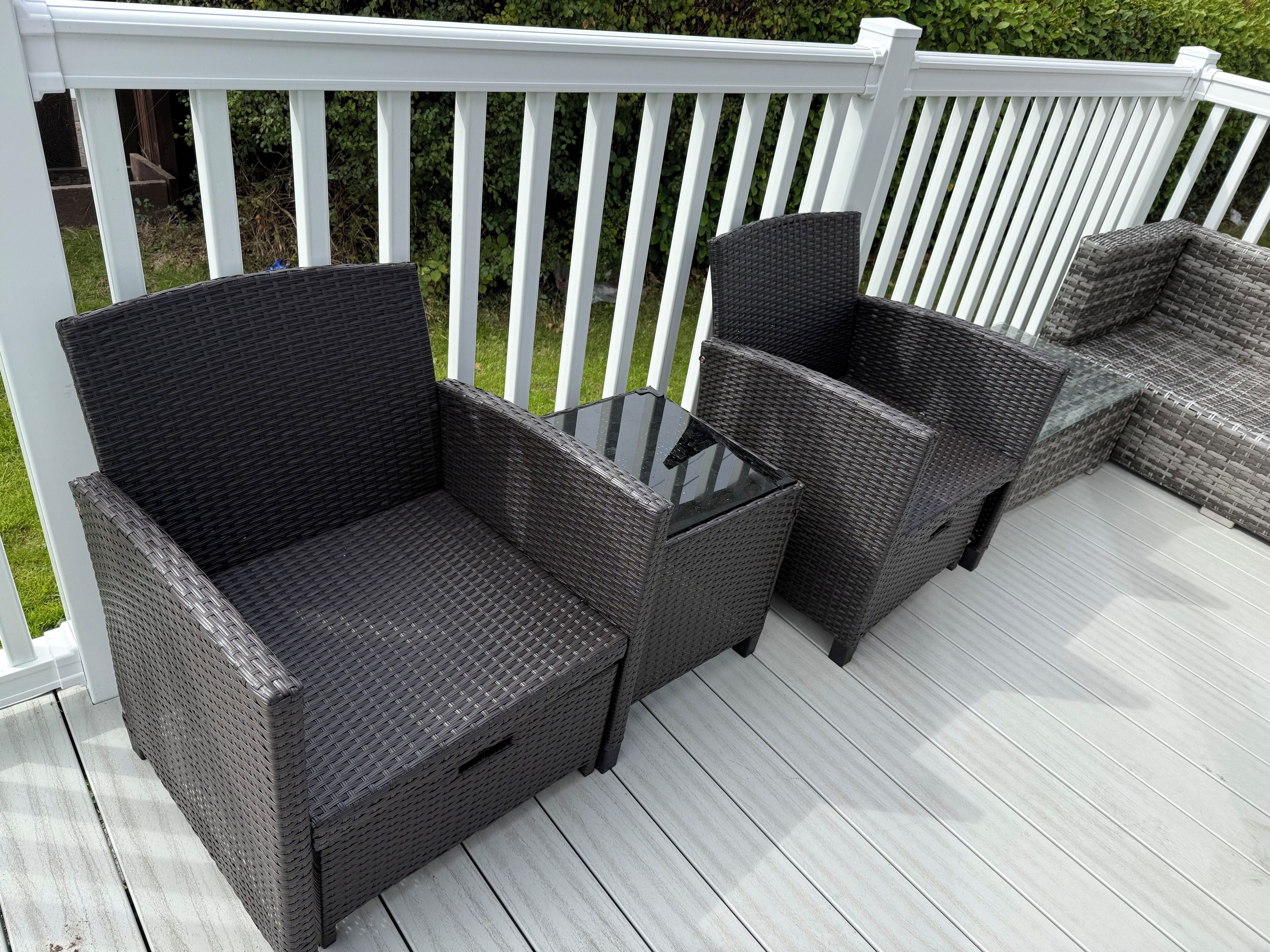 A deck with wicker furniture, including two chairs and a small table.