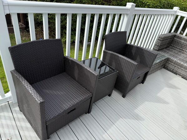 A deck with wicker furniture, including two chairs and a small table.