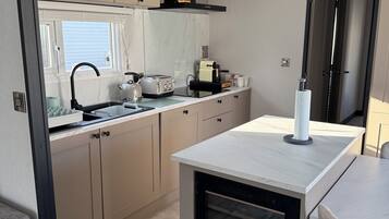 A compact kitchenette with a built-in oven, a sink, and a window above the counter.