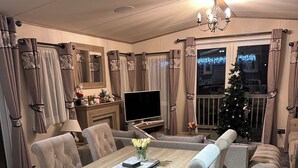 Een eethoek met een houten tafel en stoelen, een televisie en een kerstboom.