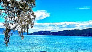A lake with mountains in the background, a clear sky, and a metal railing in the foreground. - KALLISTI beachfront/lavish decoration/15 steps to water/superb sea view/115m2 (Kefalonia)