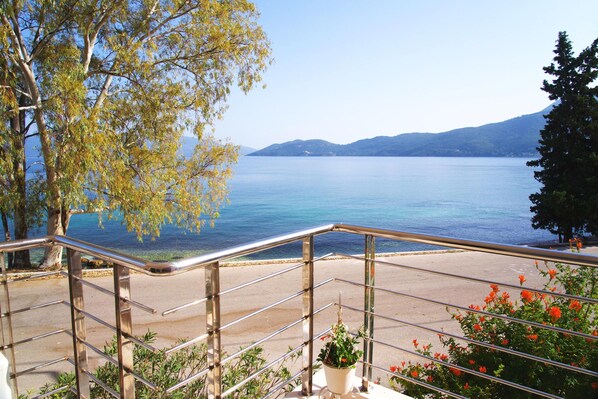 A balcony with a metal railing overlooking a lake and mountains.