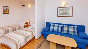 Una habitació amb dos llits, un sofà blau, una taula de fusta petita i llums penjades a la paret.