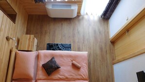 Una habitación de madera con una cama, un ventanal y un equipo de aire acondicionado.