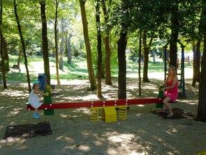 Children can play on the swings and seesaw in this shaded playground area.