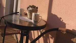 Una mesa redonda de vidrio con dos tazas blancas y una cesta tejida con una planta.