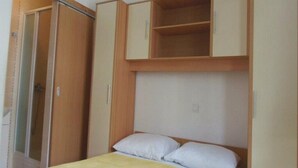 Un dormitorio con una cama, un armario y una estantería empotrada sobre la cama.