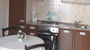 Una cocina con estufa, lavamanos, armarios y una mesa de comedor con sillas.
