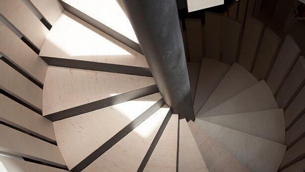 A spiral staircase with a modern design, featuring a series of wooden steps and metal railings.