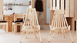 A kitchen with wooden chairs and tables, a person walking, and wooden cabinets.