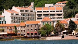 A coastal hotel with multiple buildings, a waterfront view, and a small dock with boats. - Monte Casa Spa And Wellness (Petrovac)