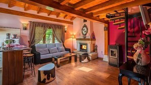 Ein gemütliches Wohnzimmer mit Kamin, Holzbalken, einer Couch und einem Essbereich.