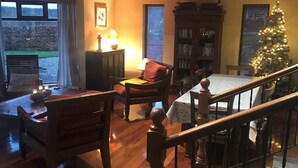 A cozy living room with a wooden staircase, a Christmas tree, and a fireplace. - Idyllic and Unique House on the Lake  (Whitegate)
