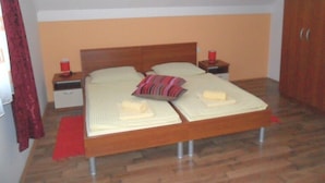 Un dormitorio con una cama de madera, dos mesitas de noche, un armario y una alfombra roja.