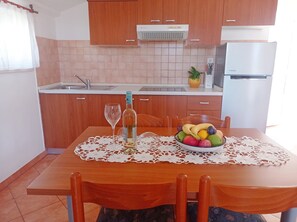 Enjoy dining and food preparation in this well-equipped kitchen with a dining table, sink, and refrigerator.