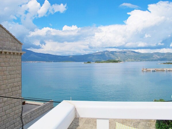 Enjoy breathtaking views of the ocean and distant mountains from this serene balcony.
