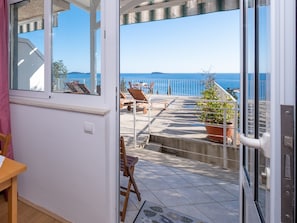 Relax on the balcony with a scenic sea view, a potted plant, and comfortable seating.