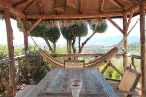 A wooden deck with a hammock and a table, overlooking a mountainous landscape. - El Caprichio - (8p) with pool at Costa del Sol (Gaucín)
