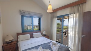 Ein Hotelzimmer mit Bett, zwei Nachttischen, einem Fenster mit Blick und einem Balkon mit Tisch und Stühlen.