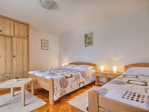 Two comfortable beds with matching headboards, a wardrobe, and a small table with a plant.