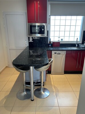 A kitchen with a black countertop, stainless steel appliances, and red cabinets. - Beautiful Superior Deluxe Home/Private sun Terrace open views 5gwifi+Netflix tv+ (municipal de mogan, ARGUINEGUIN)