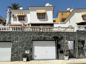 A residential building with a stone facade, white garage doors, and a gated entrance.