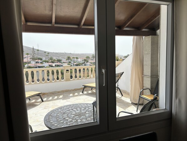 Un balcon avec un sol carrelé, une table et deux chaises.