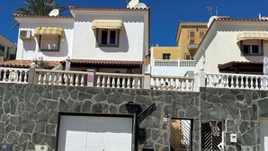 A residential building with a stone facade, a gated entrance, and a garage door. - Superior Deluxe Vacation Home with open views Privat sun Terrace & 5G WiFi (municipal de mogan, ARGUINEGUIN)