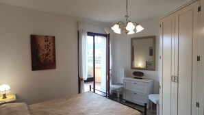 Une chambre à coucher avec un lit, une commode, un miroir et un tableau accroché au mur.