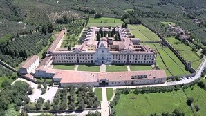 Eine Vogelperspektive auf einen großen, historischen Gebäudekomplex mit symmetrischer Architektur, umgeben von gepflegten Gärten und einem Burggraben.